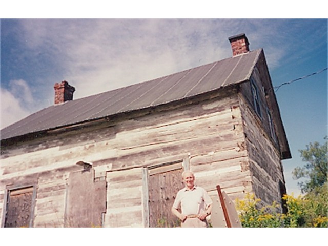 Manson in front of his log cabin birthplace in Thorne, Quebec